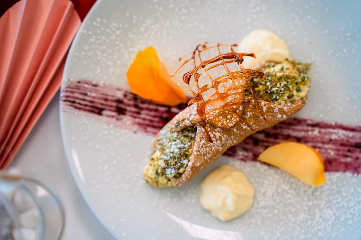 Pistachio cannoli with caramel, powdered sugar and cream